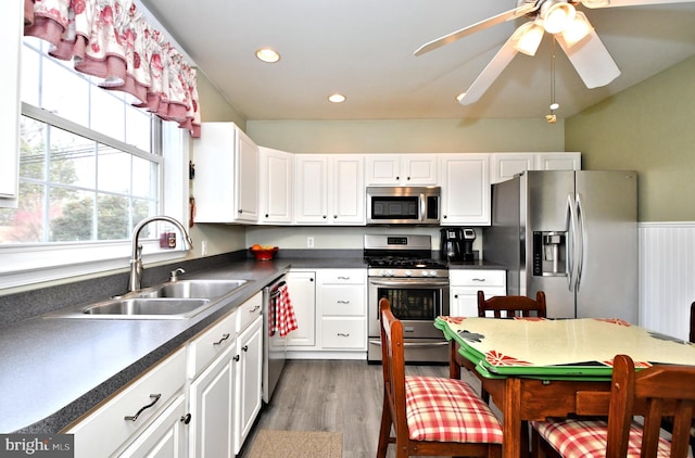 kitchen featuring stainless steel appliances, ceiling fan, hardwood / wood-style floors, sink, and white cabinetry