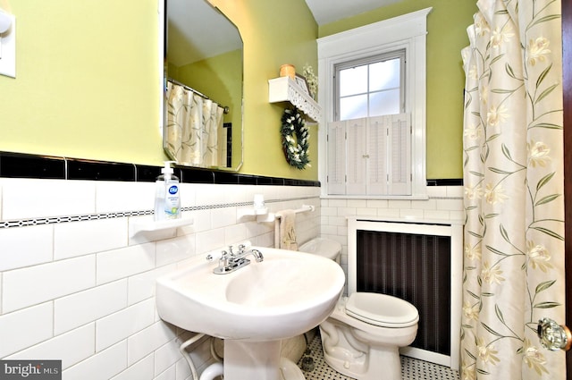 bathroom with radiator heating unit, sink, tile walls, and toilet