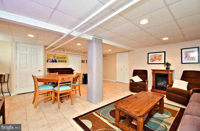 living room featuring a drop ceiling and light tile patterned floors