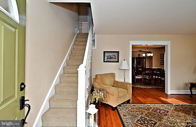 stairs featuring an inviting chandelier and wood-type flooring