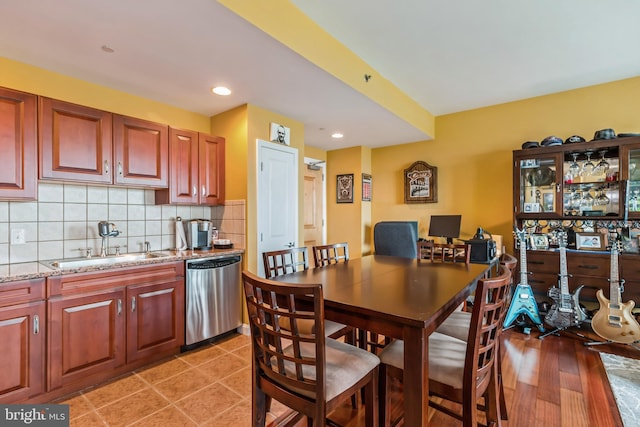 kitchen with light stone counters, tasteful backsplash, dishwasher, light hardwood / wood-style flooring, and sink