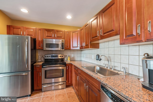 kitchen with tasteful backsplash, light stone countertops, light tile patterned floors, stainless steel appliances, and sink