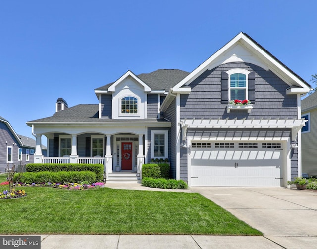 view of front of property featuring a garage, covered porch, and a front yard