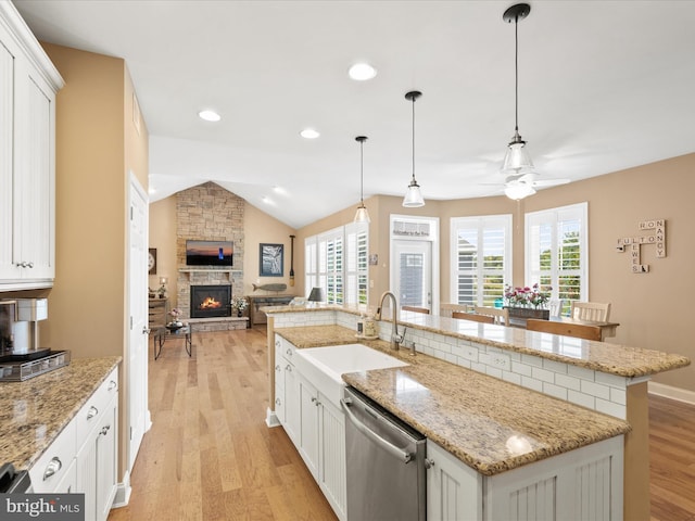 kitchen with a fireplace, vaulted ceiling, dishwasher, and a wealth of natural light