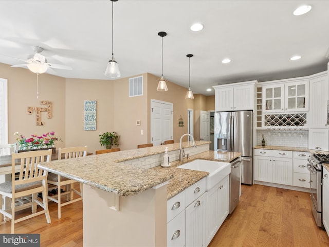 kitchen with an island with sink, a kitchen breakfast bar, light hardwood / wood-style floors, and appliances with stainless steel finishes