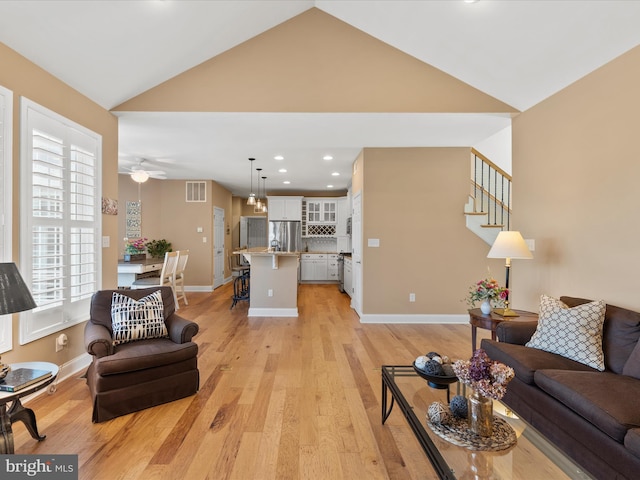 living room featuring light wood-type flooring, lofted ceiling, and ceiling fan