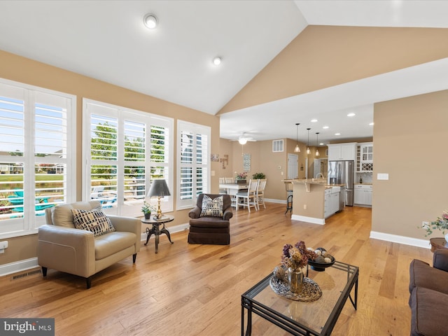 living room with high vaulted ceiling, light wood-type flooring, and sink