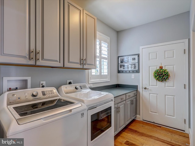 laundry area featuring cabinets, light hardwood / wood-style floors, and washer and dryer