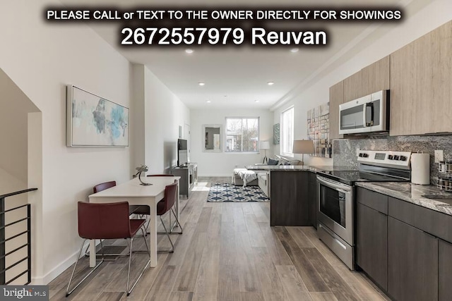 kitchen featuring appliances with stainless steel finishes, dark stone counters, dark hardwood / wood-style floors, and tasteful backsplash