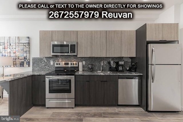 kitchen featuring light stone countertops, stainless steel appliances, hardwood / wood-style flooring, and sink