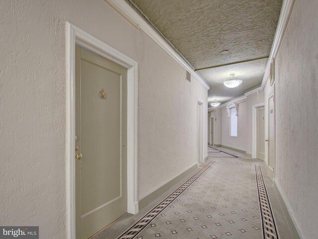 hall featuring a textured ceiling and crown molding