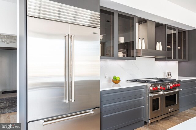 kitchen featuring wine cooler, light stone countertops, premium appliances, light hardwood / wood-style flooring, and sink