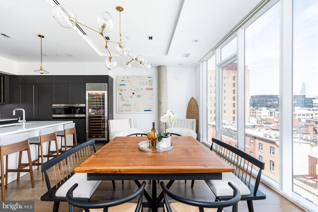 bar featuring wine cooler, light hardwood / wood-style floors, stainless steel oven, and gray cabinetry