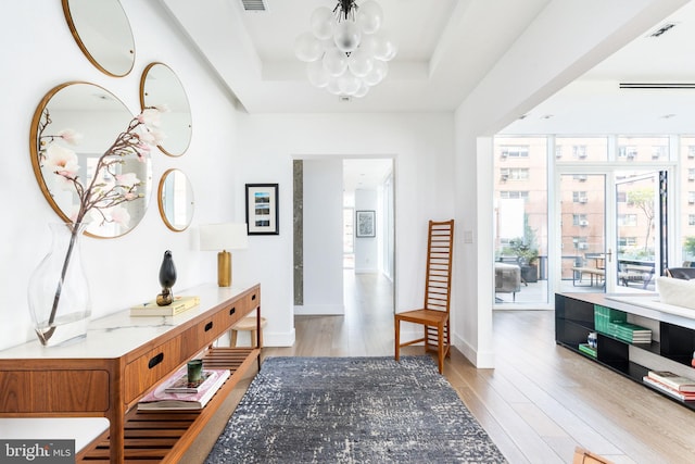 entrance foyer featuring light hardwood / wood-style floors, a tray ceiling, and a notable chandelier