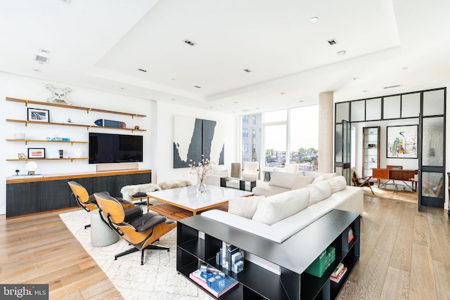 living room featuring floor to ceiling windows, light hardwood / wood-style floors, and a raised ceiling