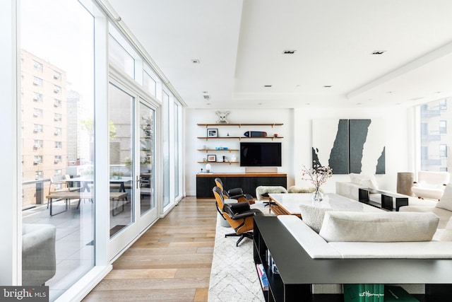 living room with light wood-type flooring and a tray ceiling