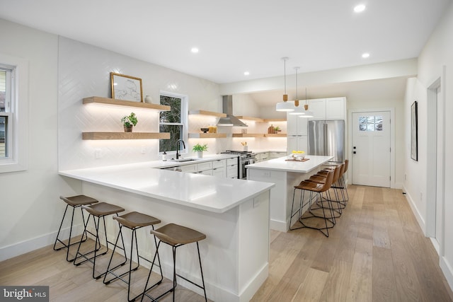 kitchen with plenty of natural light, light hardwood / wood-style floors, decorative light fixtures, high quality appliances, and a breakfast bar