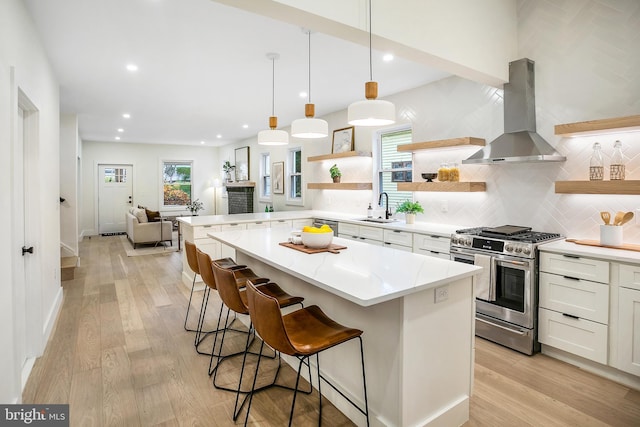 kitchen featuring light wood-type flooring, gas stove, extractor fan, sink, and white cabinetry