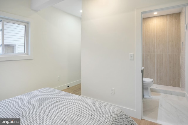 bedroom with light wood-type flooring and ensuite bathroom