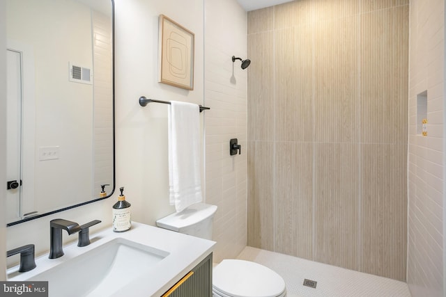 bathroom with vanity, toilet, and tiled shower