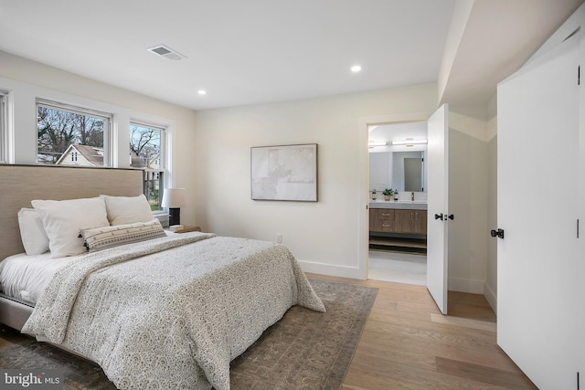 bedroom with wood-type flooring and ensuite bath