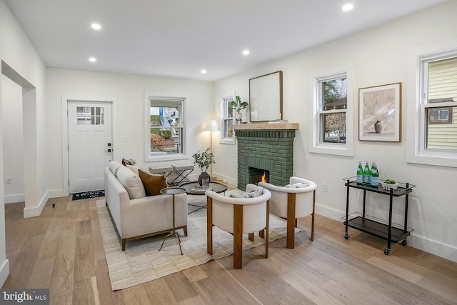 living room featuring light hardwood / wood-style floors, a brick fireplace, and plenty of natural light