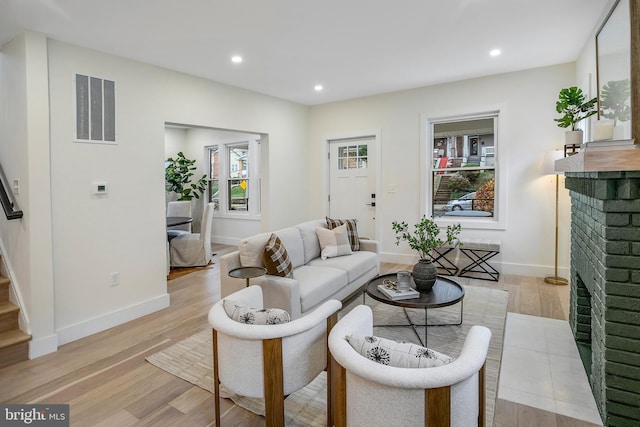 living room with a brick fireplace and light hardwood / wood-style flooring