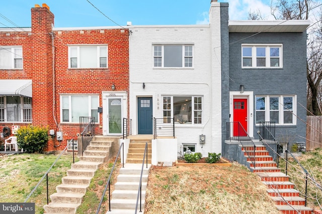 multi unit property featuring brick siding, a chimney, and a front lawn