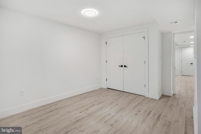 unfurnished bedroom featuring visible vents, baseboards, light wood-style floors, and a closet