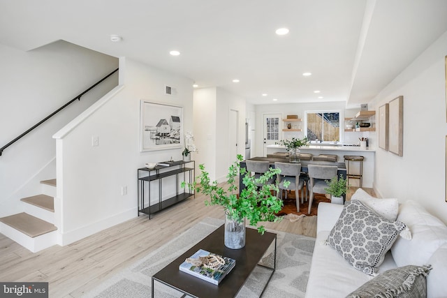 living room featuring stairway, recessed lighting, light wood-style floors, and visible vents
