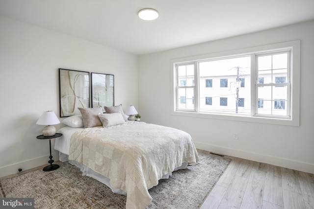 bedroom featuring multiple windows, wood finished floors, and baseboards