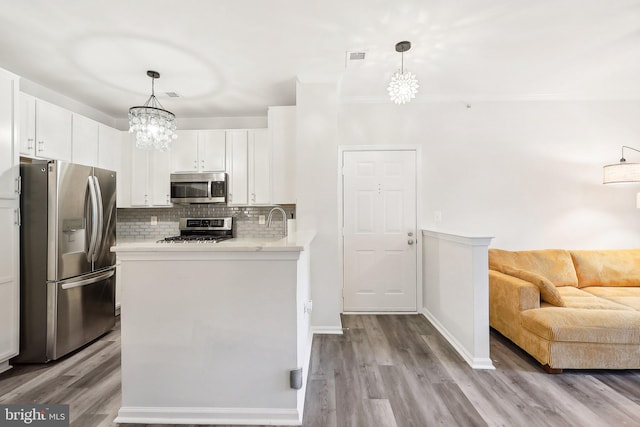 kitchen featuring stainless steel appliances, white cabinetry, light hardwood / wood-style floors, and decorative light fixtures