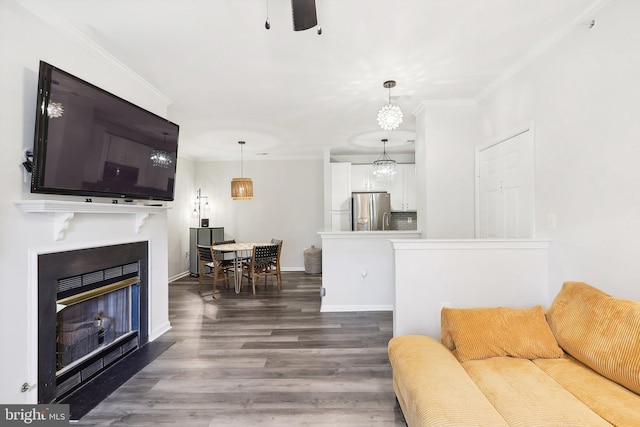 living room featuring ornamental molding, ceiling fan with notable chandelier, and dark hardwood / wood-style floors