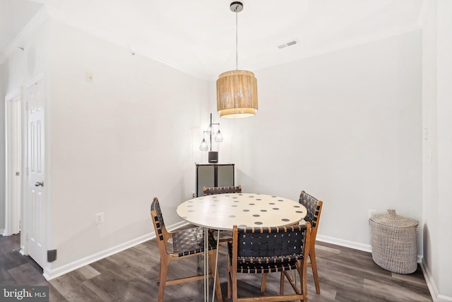 dining area with ornamental molding and dark hardwood / wood-style flooring