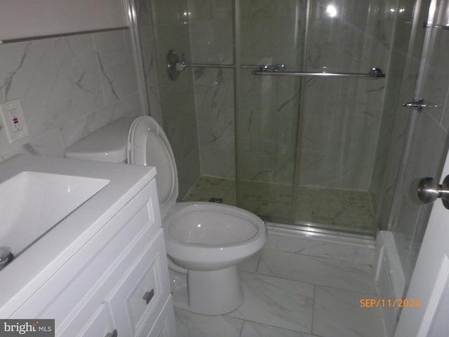 bathroom with vanity, tile walls, toilet, a marble finish shower, and marble finish floor