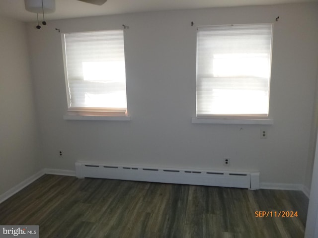 unfurnished room with ceiling fan, dark hardwood / wood-style floors, and a baseboard heating unit