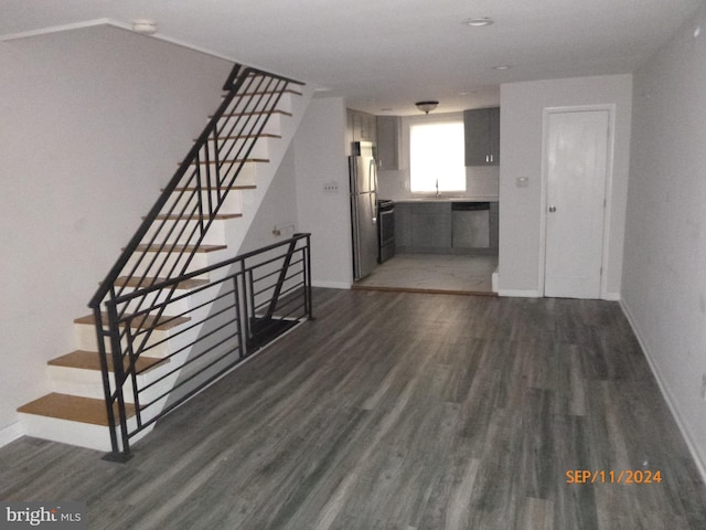unfurnished living room with a sink, baseboards, stairway, and wood finished floors