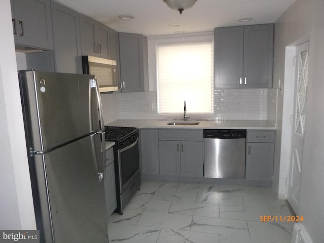 kitchen featuring stainless steel appliances, gray cabinets, tasteful backsplash, and sink