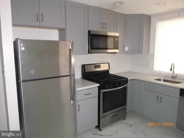 kitchen featuring gray cabinets, sink, stainless steel appliances, and tasteful backsplash