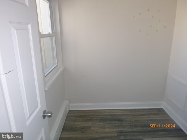 spare room with baseboards and dark wood-style floors