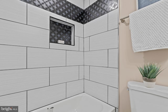 bathroom featuring toilet and tiled shower / bath