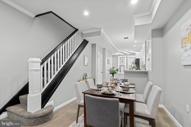 dining space with crown molding and light hardwood / wood-style flooring