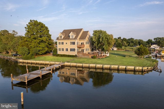 back of property with a lawn and a water view