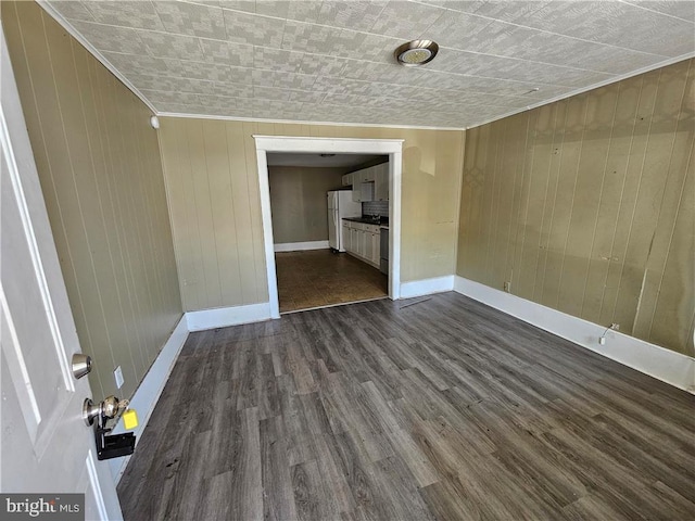 unfurnished room with ornamental molding, wooden walls, and dark wood-type flooring