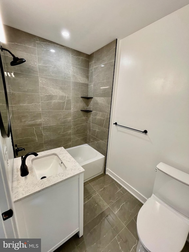 full bathroom featuring tiled shower / bath, vanity, and toilet