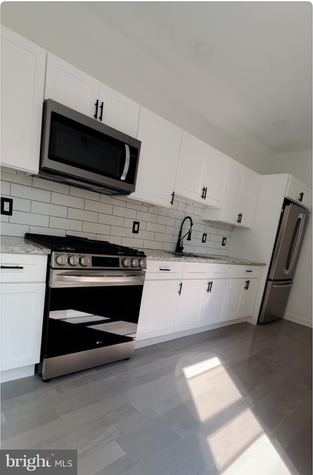 kitchen featuring stainless steel appliances, sink, tasteful backsplash, and white cabinetry