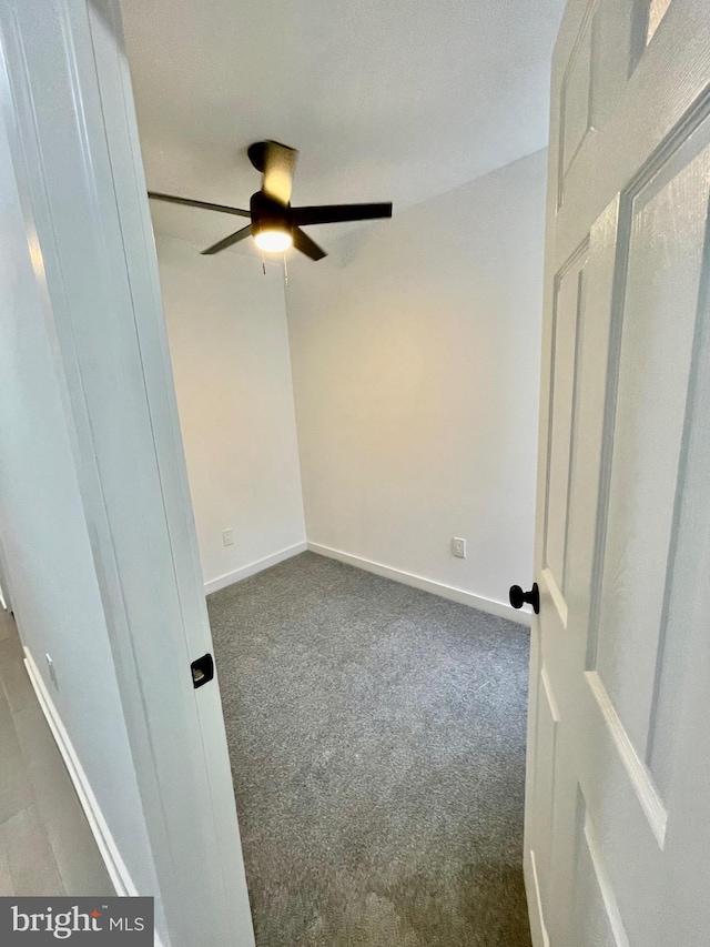 empty room featuring ceiling fan and dark carpet