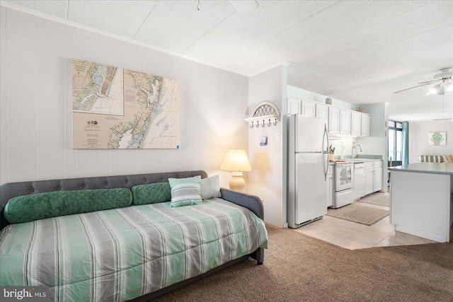 carpeted bedroom with white refrigerator, sink, ceiling fan, and a textured ceiling