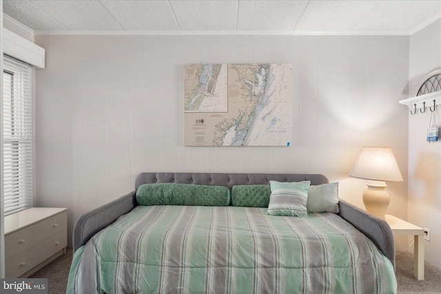 carpeted bedroom featuring ornamental molding and wood walls