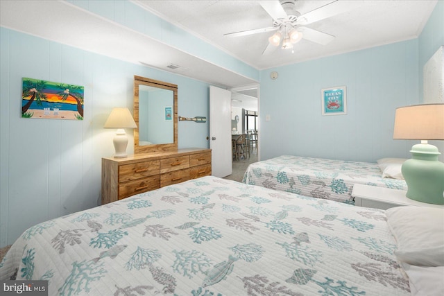 bedroom featuring ceiling fan, wooden walls, and crown molding